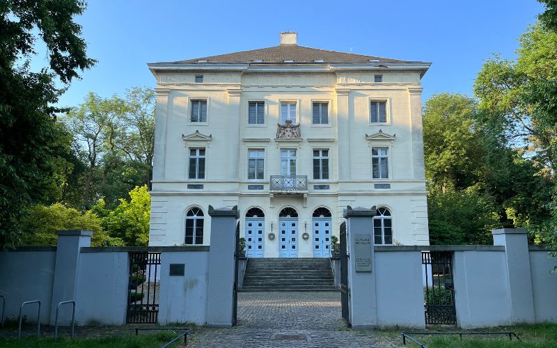 Schloss Mickeln mit seinem Eingangsprtal und einigen Bäumen daneben